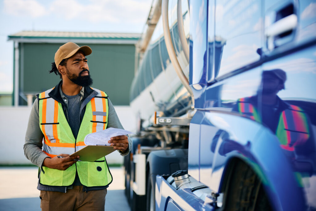 Man holding a clip board and pen inspecting his truck 
