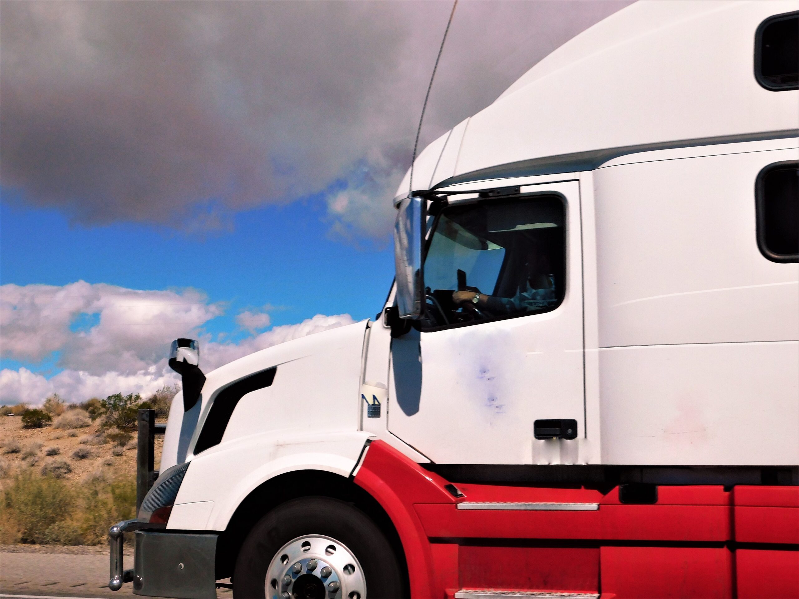Side shot a white and red semi truck cab