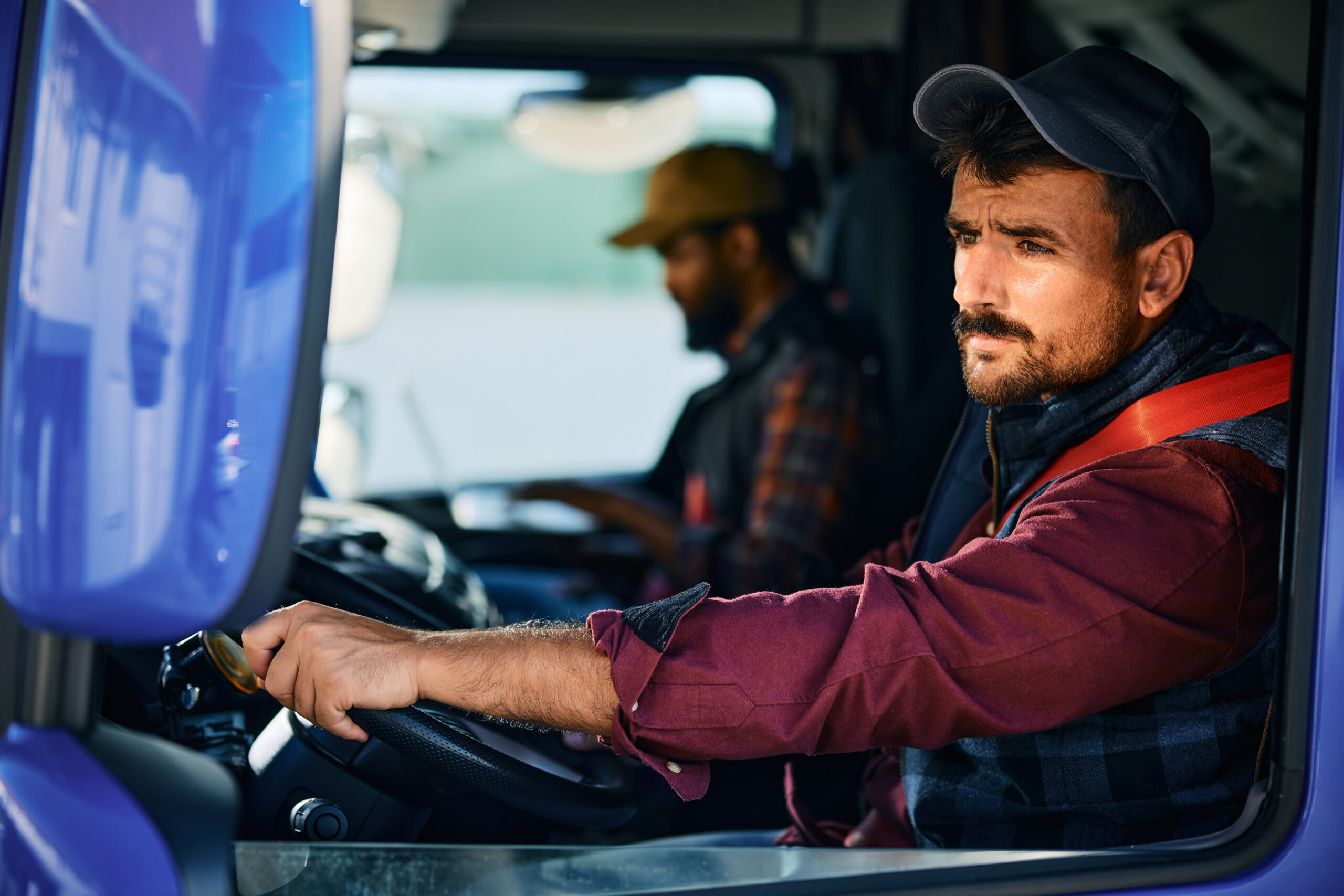 Truck driver looking at side view mirror while driving in reverse.