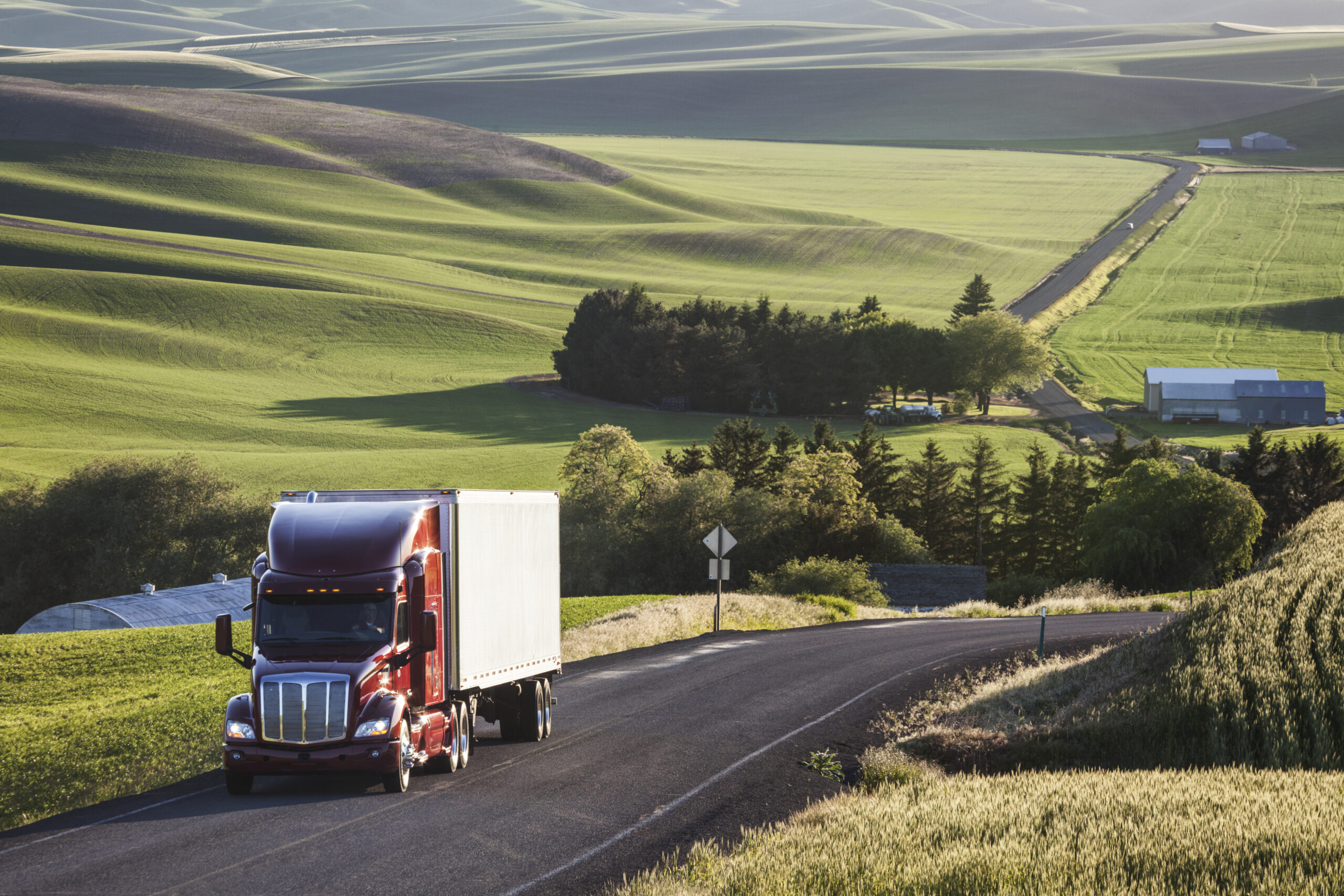 commercial truck driving though wheat fields of eastern Washington, USA at sunset.